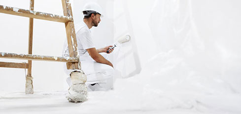 Man painting a wall white